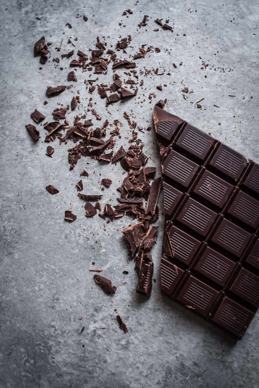 close up view of ingredient for mint mocha chocolate chunk ice cream: dark chocolate bar partially chopped up