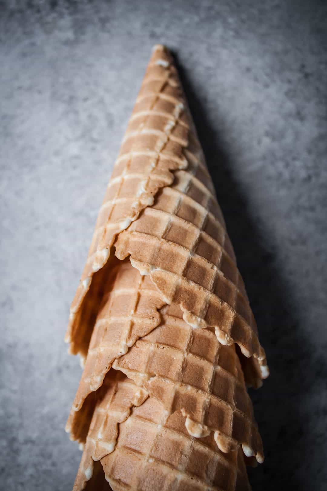 close up shot of three waffle cones stacked together and lying on a grey background