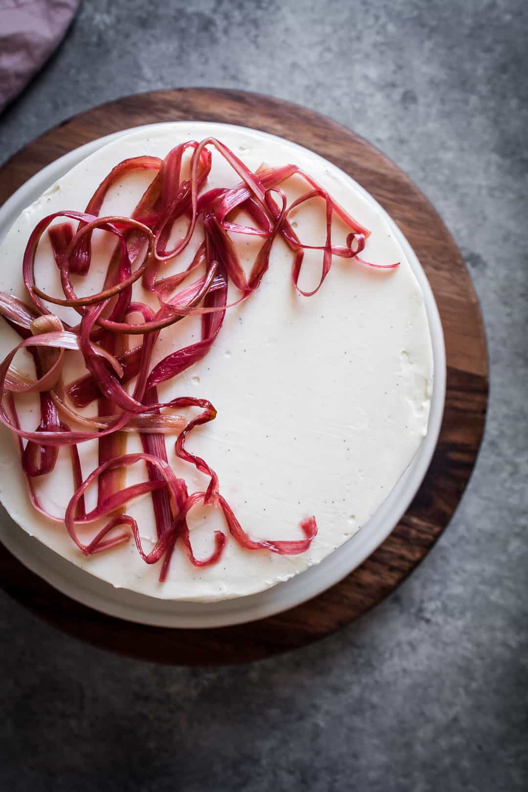 Top view close up of brown sugar cake with rhubarb compote and creme fraiche buttercream from a top view with a grey background below