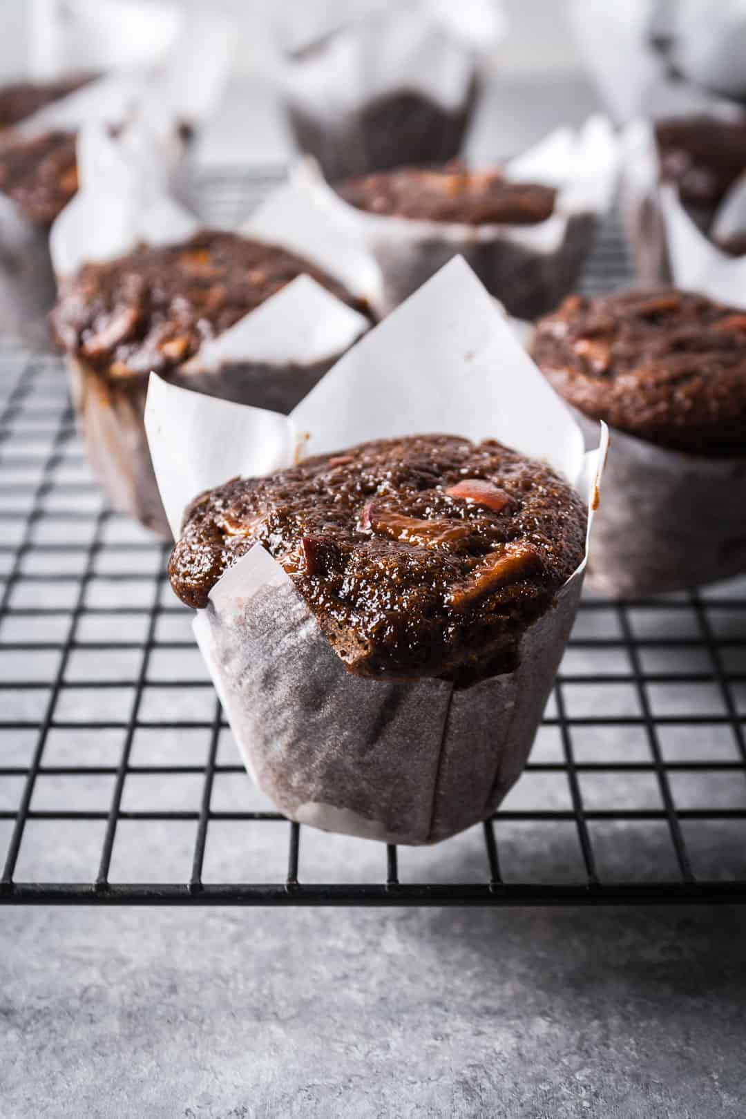 Apple ginger mini cakes in parchment paper cups with more cakes on a rack in the background