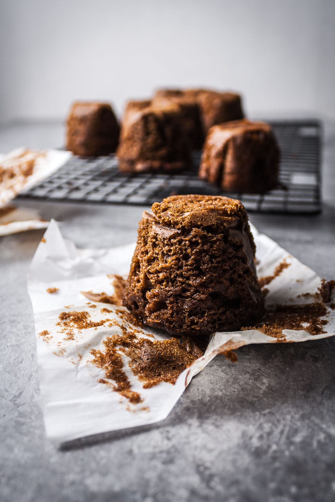 Apple ginger mini cake on parchment paper with more cakes on a rack in the background