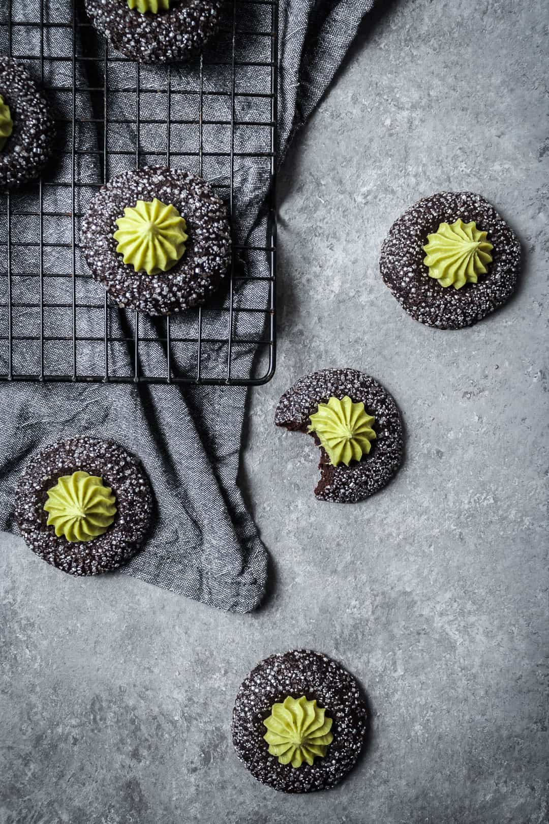 Top view of mint matcha chocolate thumbprint cookies on cooling rack and grey background