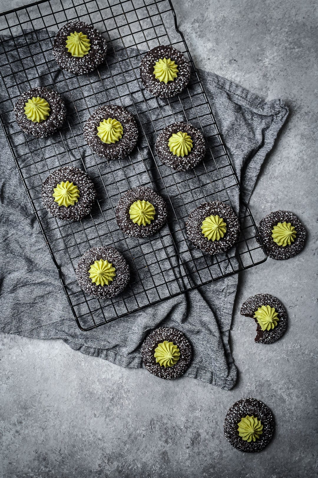 Top view of mint matcha chocolate thumbprint cookies on cooling rack and grey background