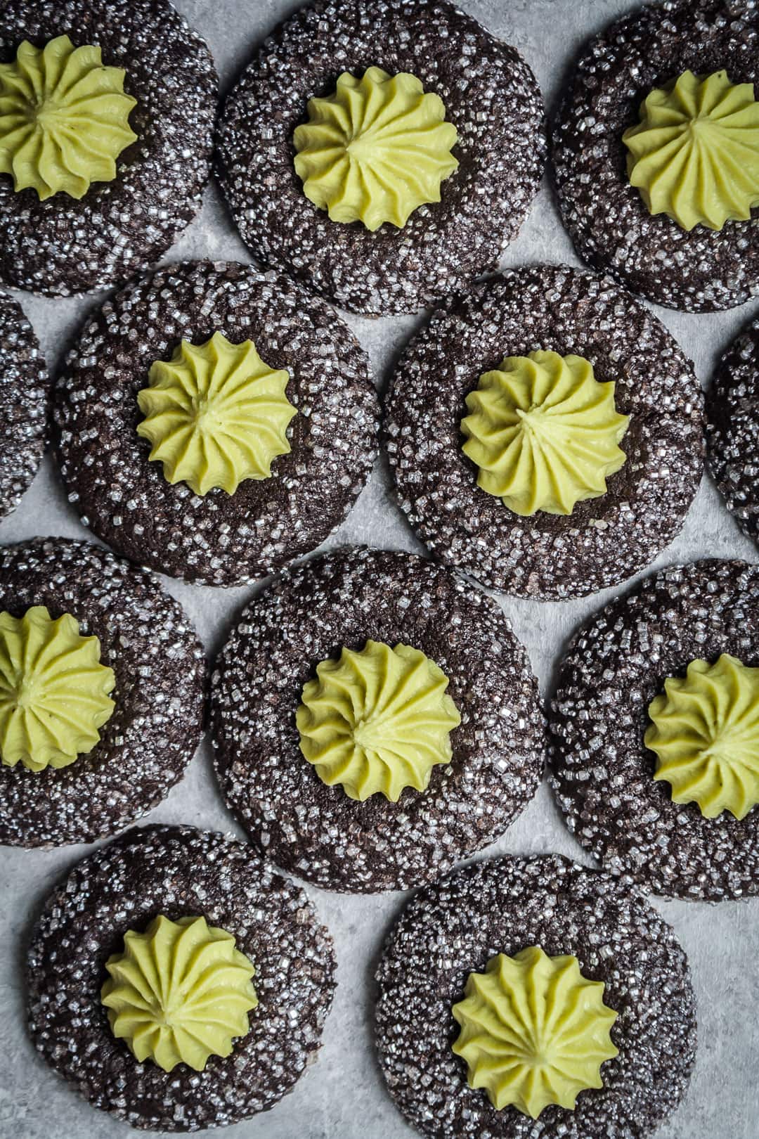 top view of mint matcha chocolate thumbprint cookies lined up on a grey background