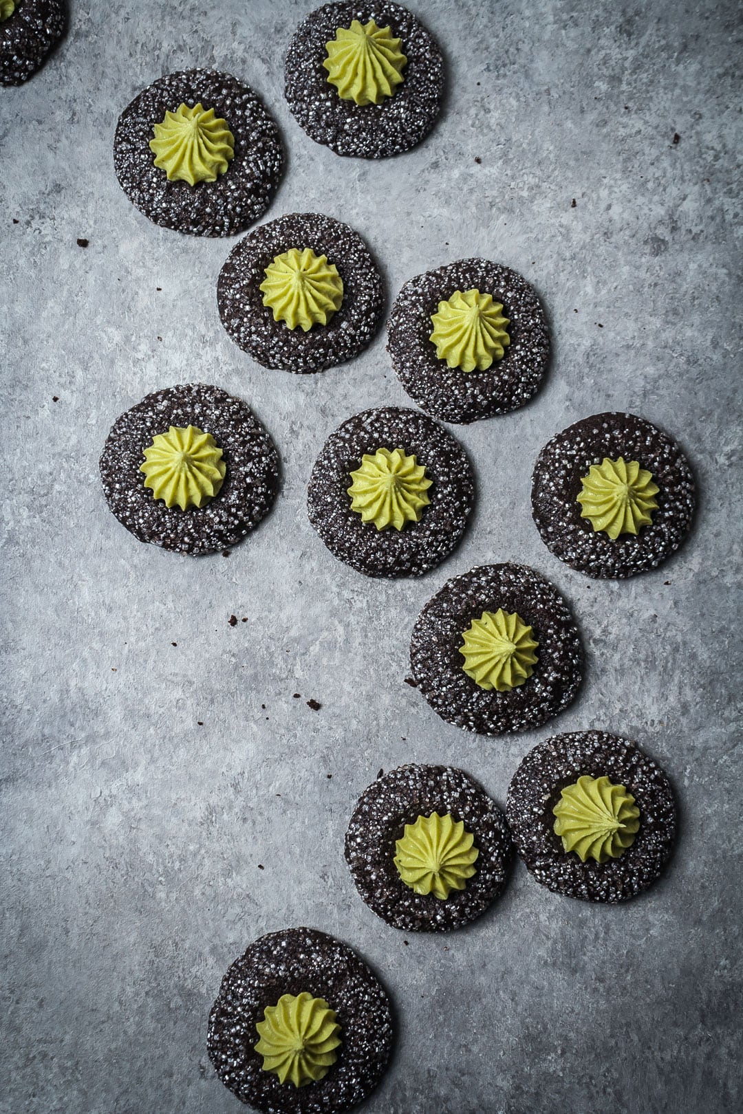 Top view of mint matcha chocolate thumbprint cookies on a grey background