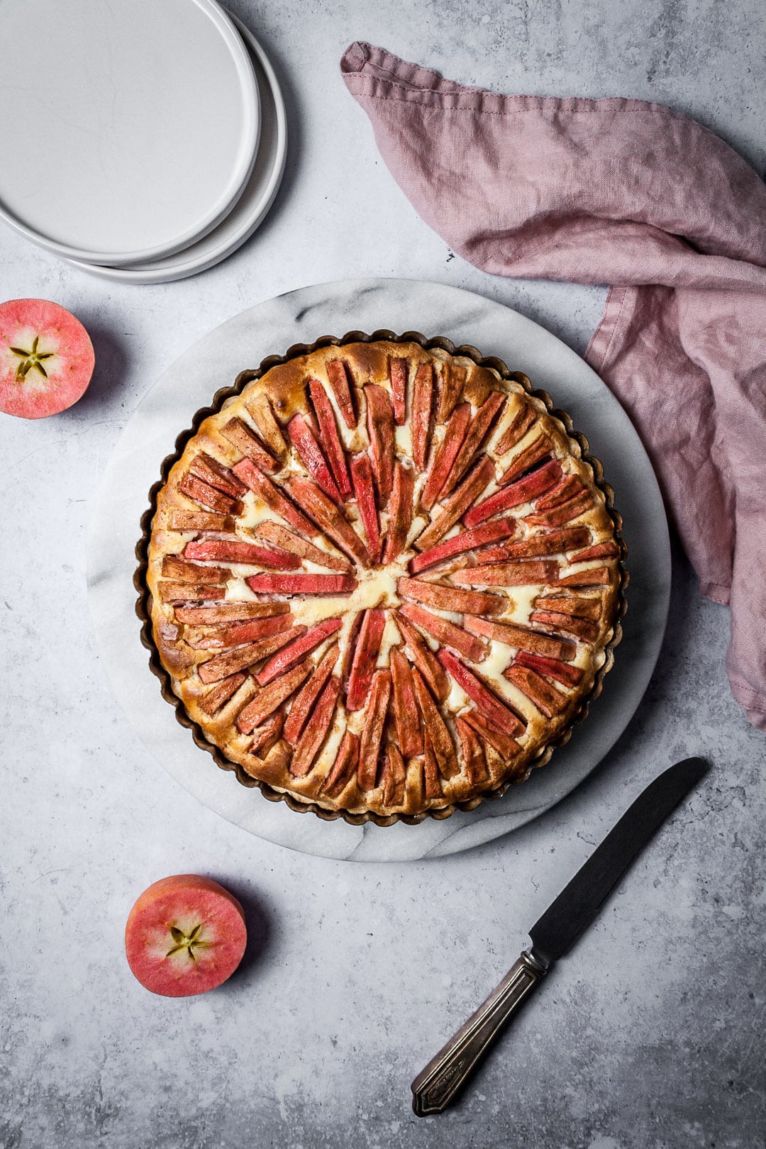 Pink Apple Tart with Cream Cheese Filling on a marble platter with a grey background