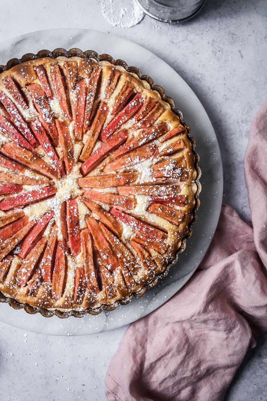 Pink Apple Tart with Cream Cheese Filling on a marble platter with a grey background