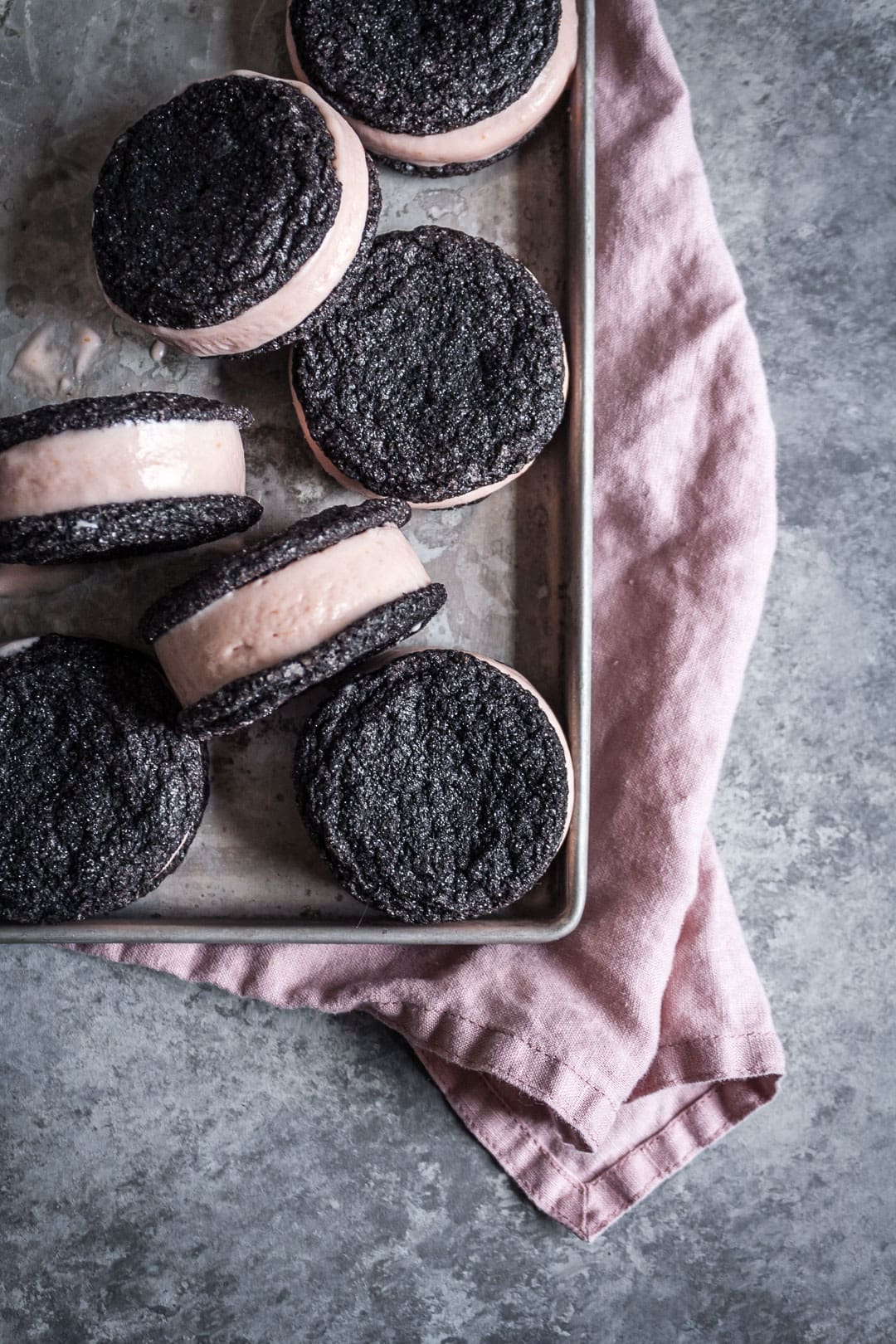 Top view of metal tray filled with chocolate blood orange ice cream sandwiches with pink linen napkin