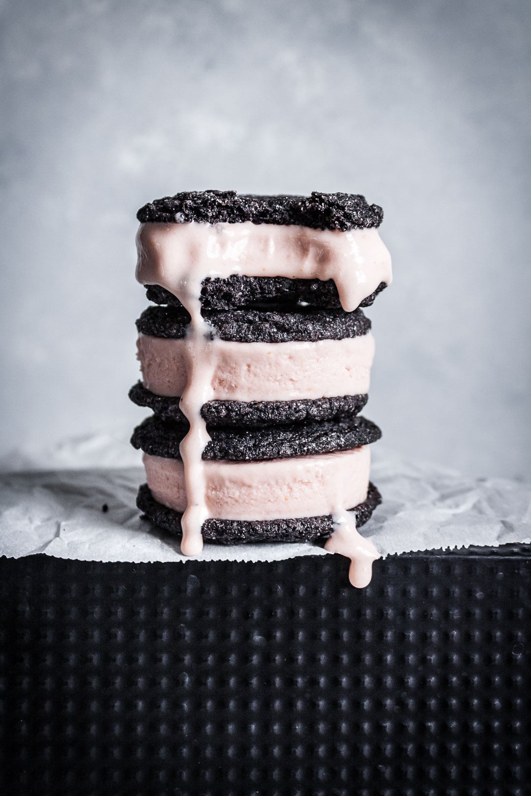 Stack of three chocolate blood orange ice cream sandwiches with bite taken out and ice cream drip
