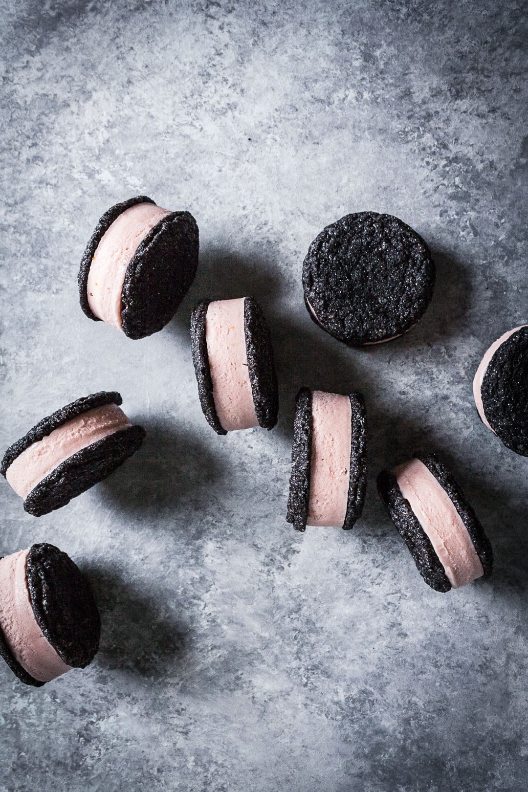 Top view of chocolate blood orange ice cream sandwiches balancing on edge on a grey background