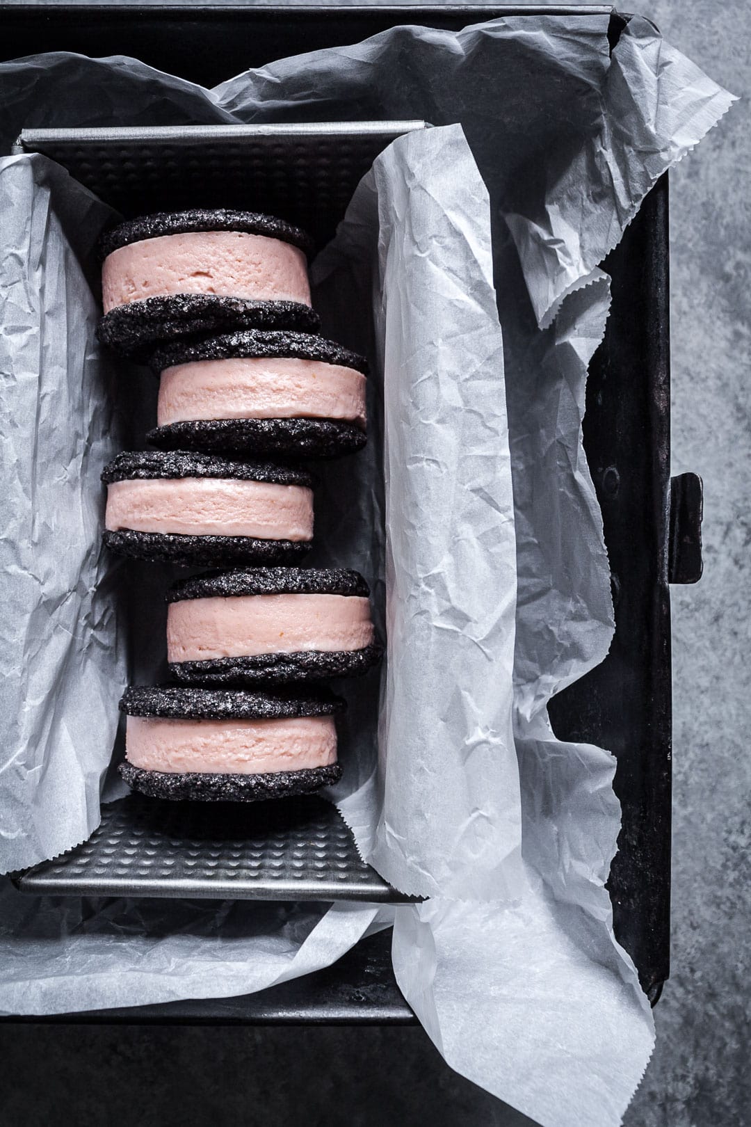 Top view of metal pan filled with chocolate blood orange ice cream sandwiches, resting on parchment paper