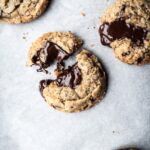Top view of freshly baked coconut chocolate chip cookies with melted pools of chocolate resting on parchment paper