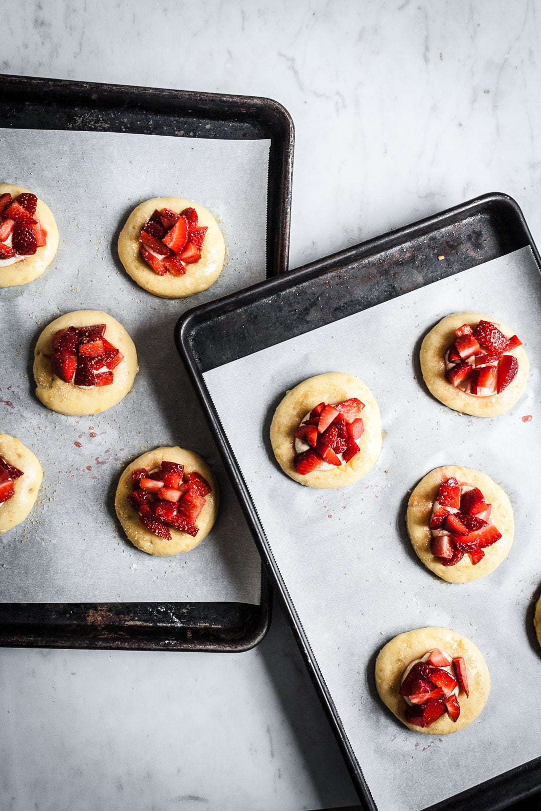 Two pans of brioche pastries with strawberries and cream cheese prior to baking