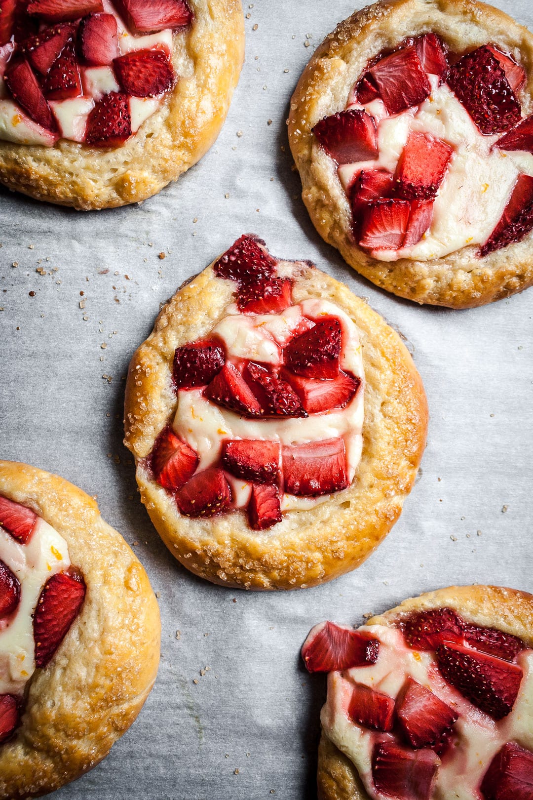 Strawberry cream cheese brioche pastries on white parchment after bakinng