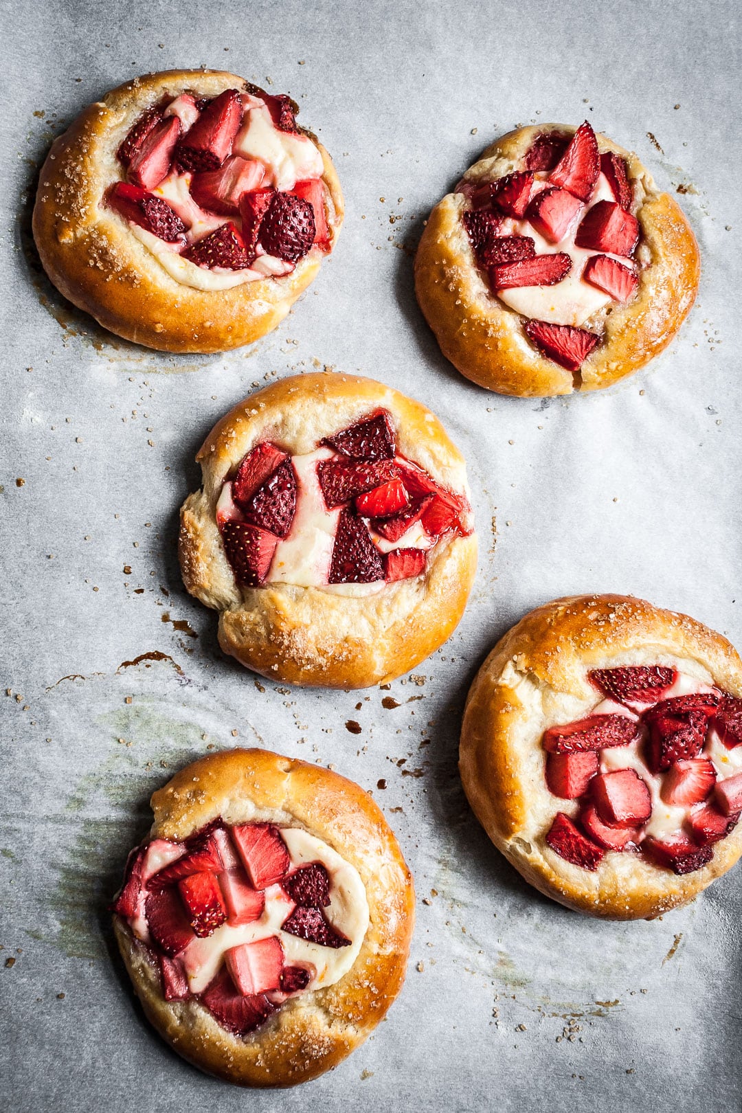 Strawberry cream cheese brioche pastries on white parchment after baking