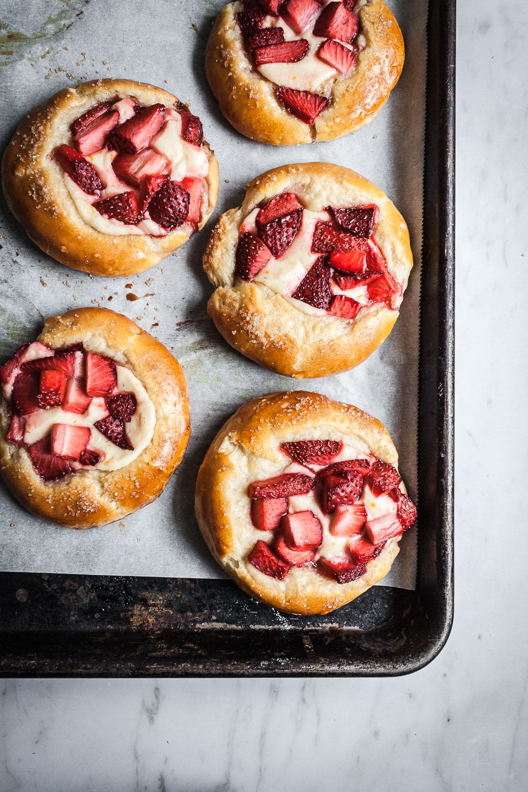 Black pan of brioche pastries after baking, resting on a marble surface