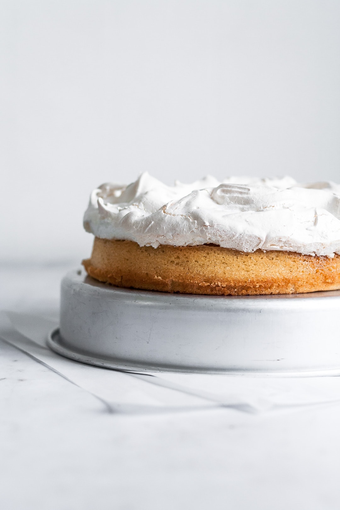 Side view of coconut cake topped with a layer of baked white meringue