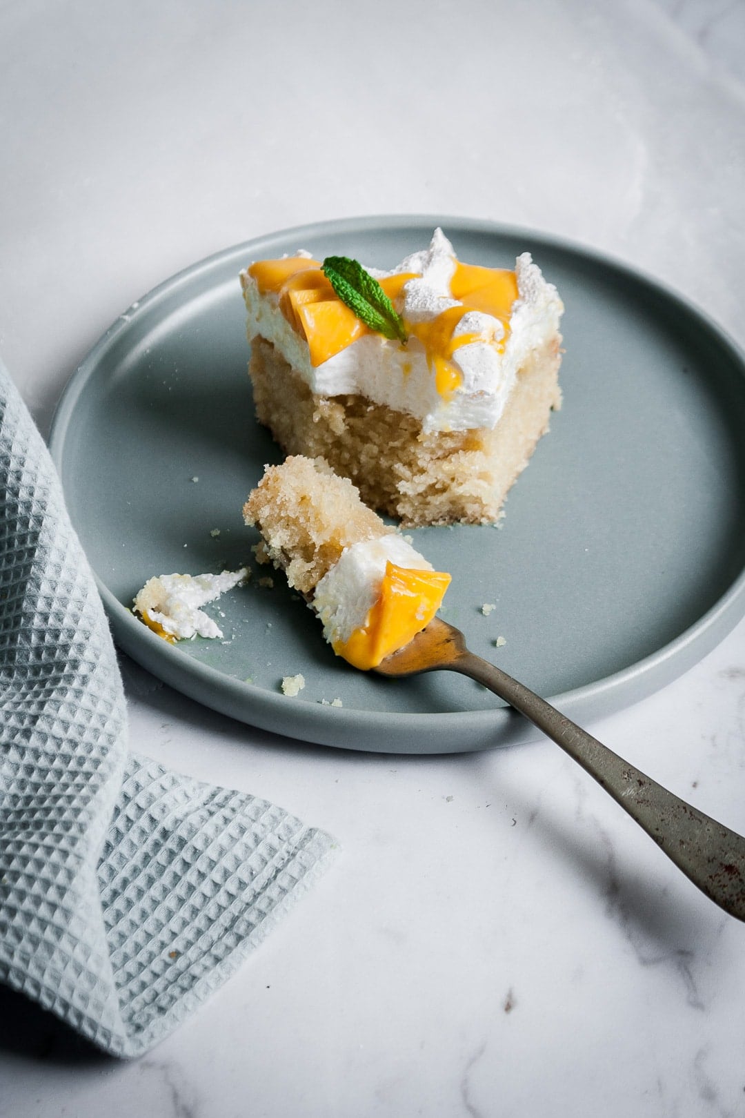 Partially eaten slice of coconut meringue cake on a blue plate