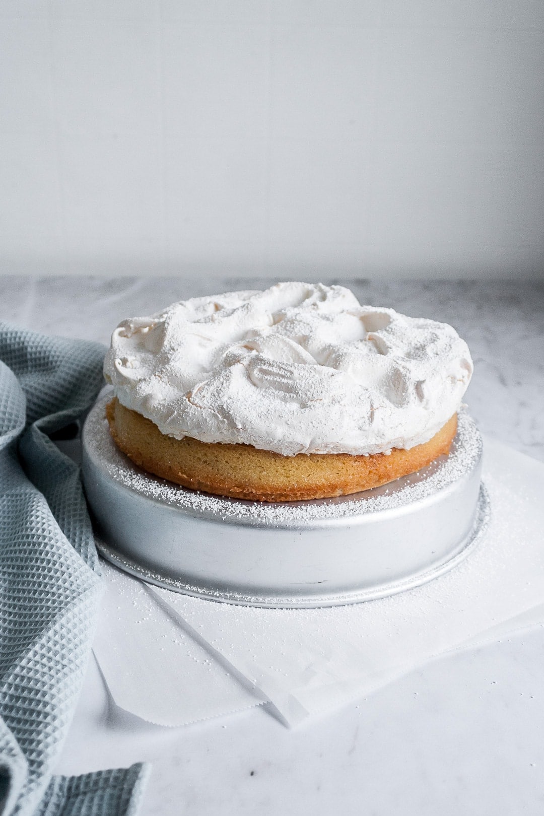 45 degree angle view of coconut cake with baked meringue layer on top on a marble background