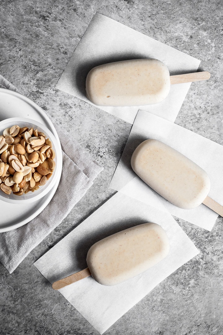 Peanut butter ice cream bars on parchment paper squares before dipping in chocolate