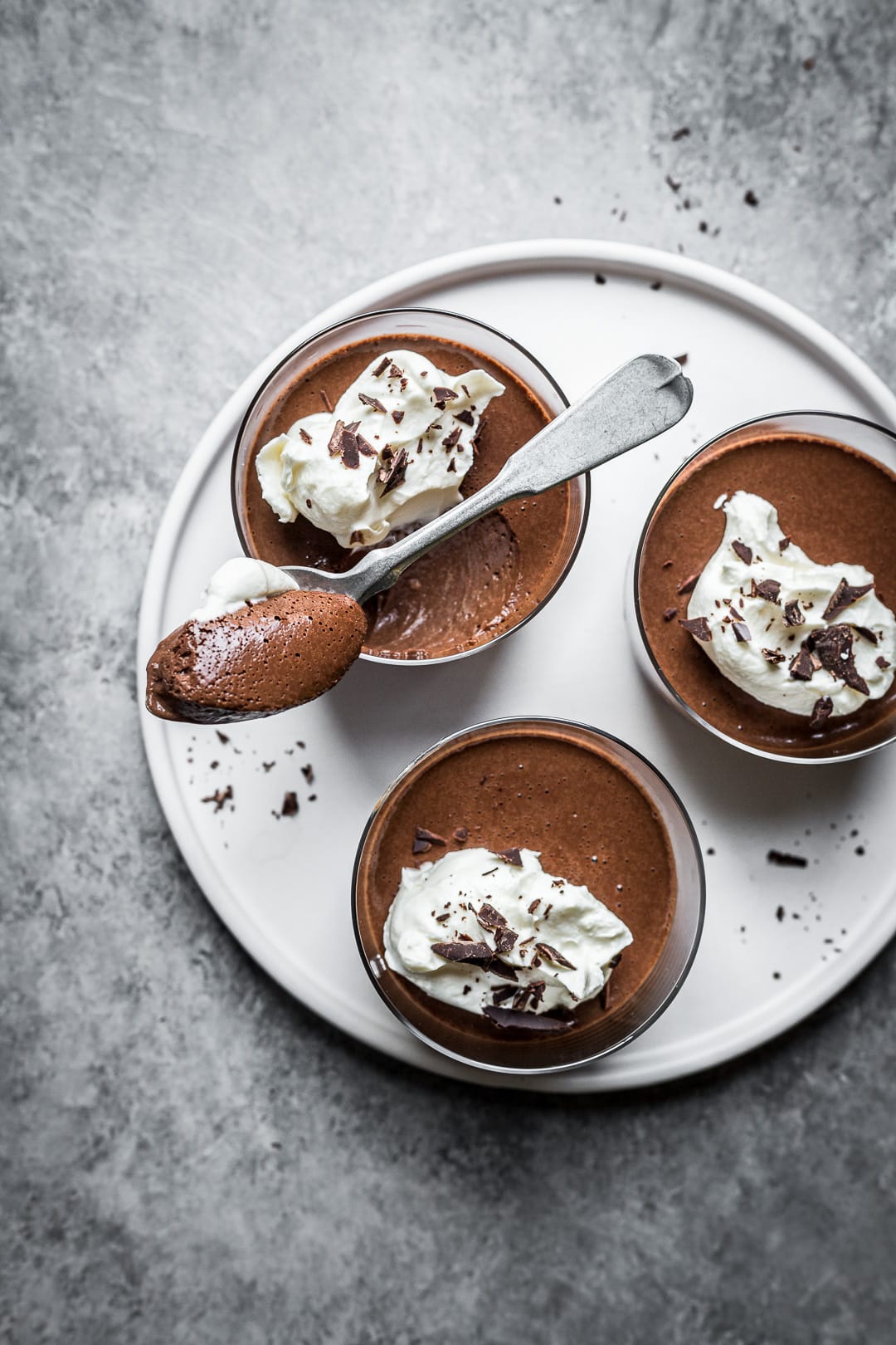 Three chocolate desserts on a white plate with a scoop full resting on one glass