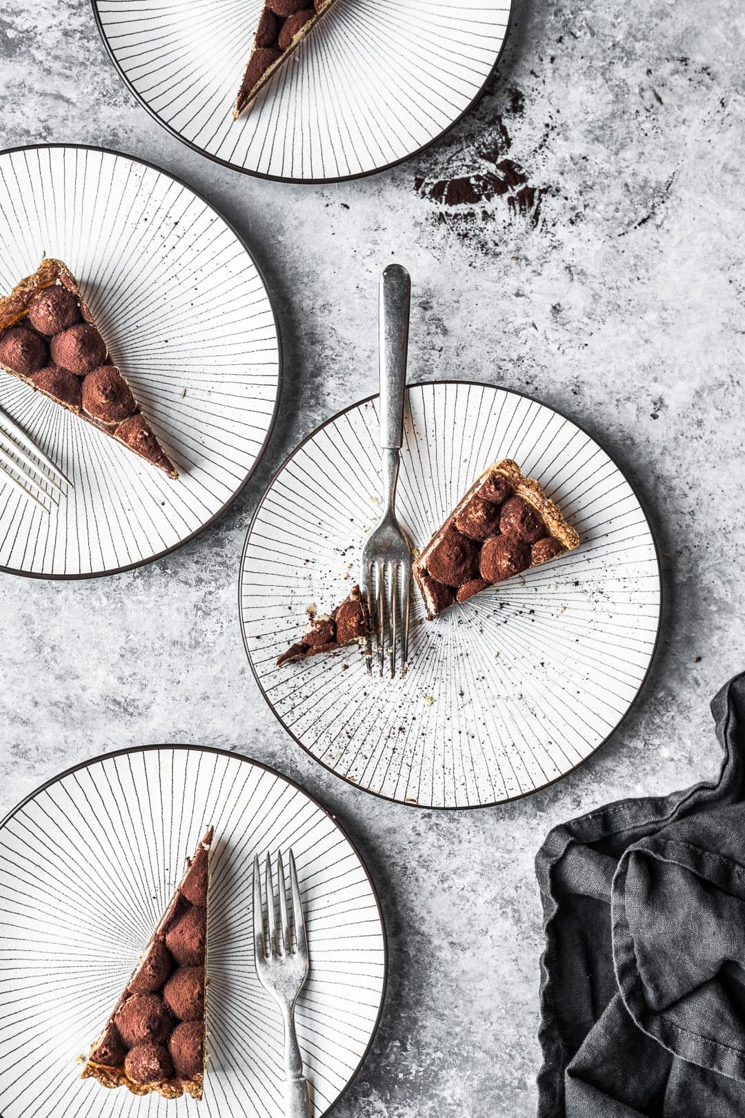 Four plates on a grey background with slices of tart and forks on plates