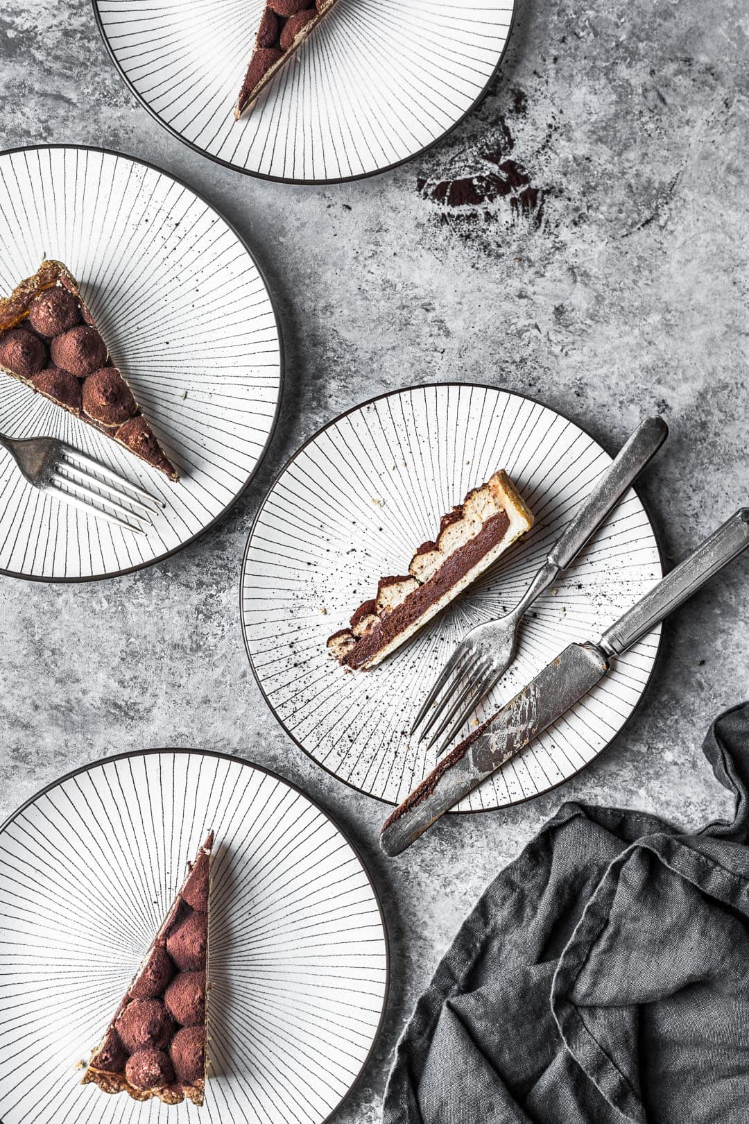 Sliced chocolate coffee mascarpone tart on plates with grey background behind