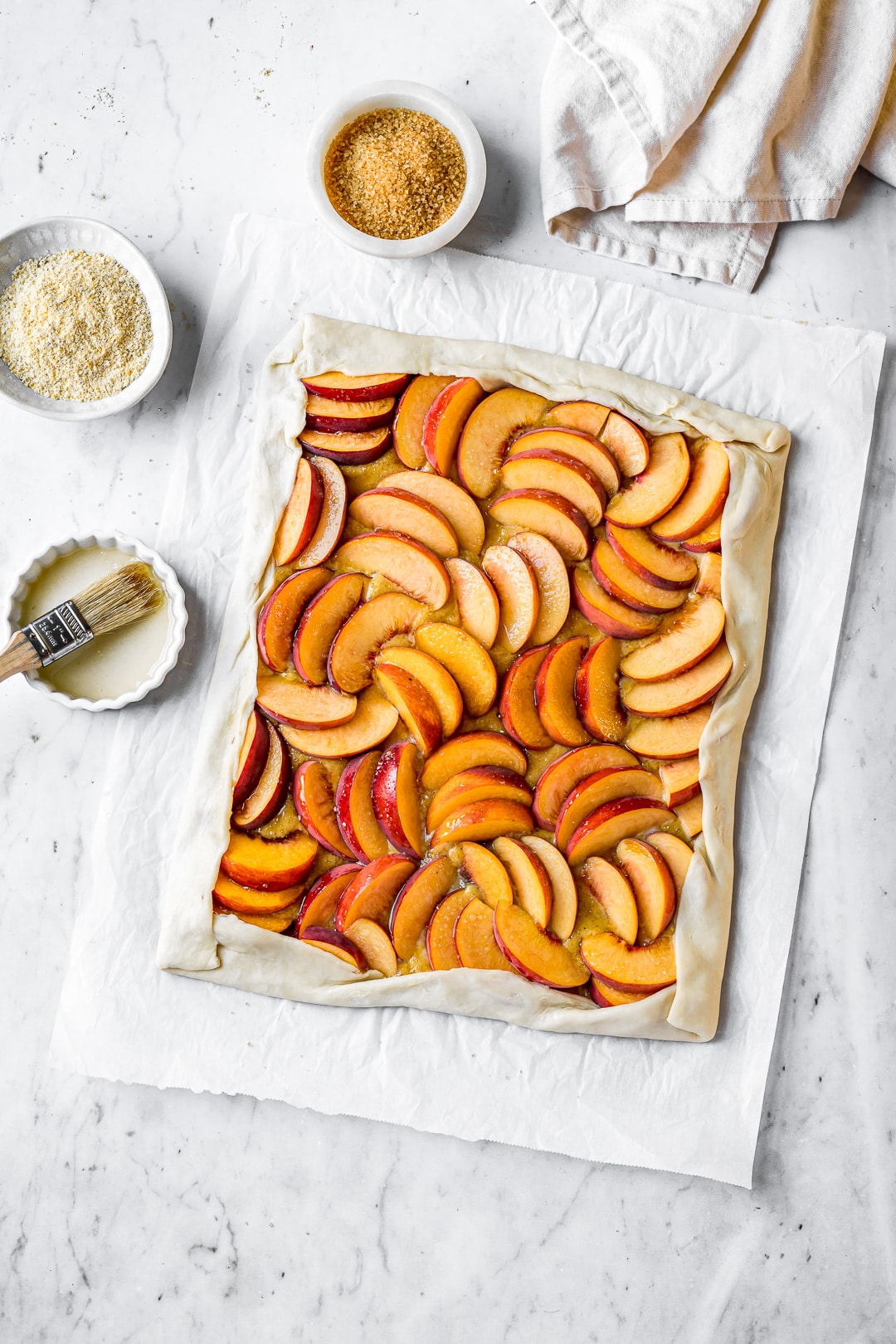 Unbaked peach galette on a white marble background