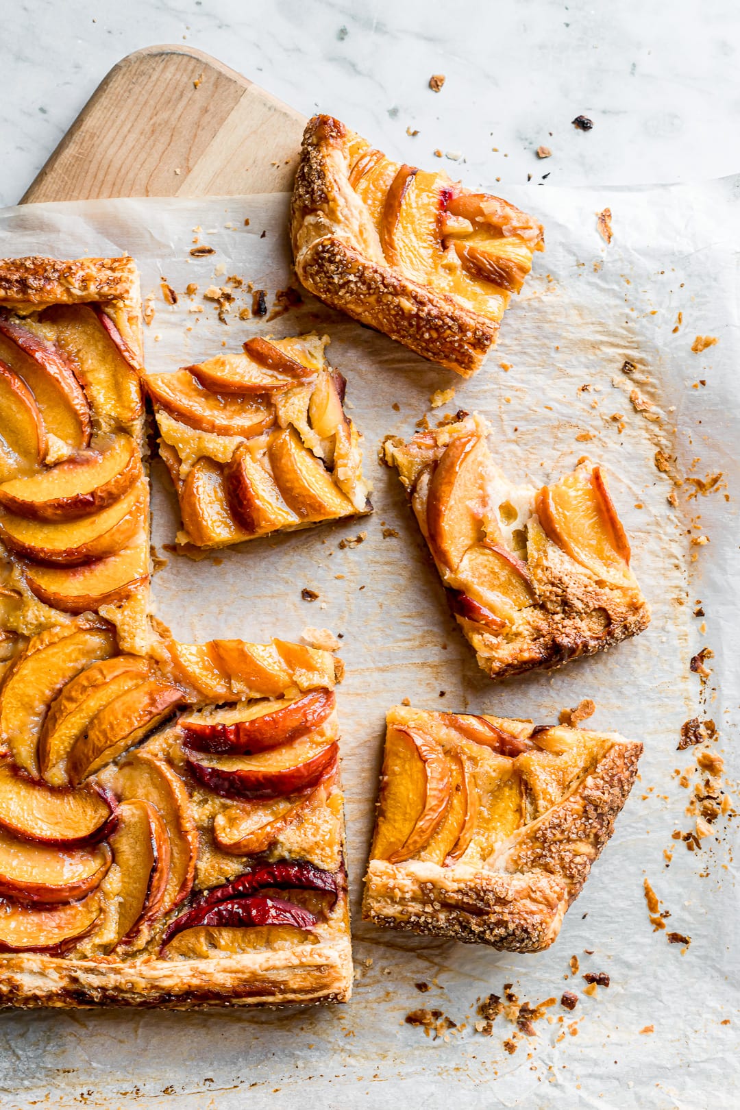 Peach galette slices on parchment paper and a cutting board