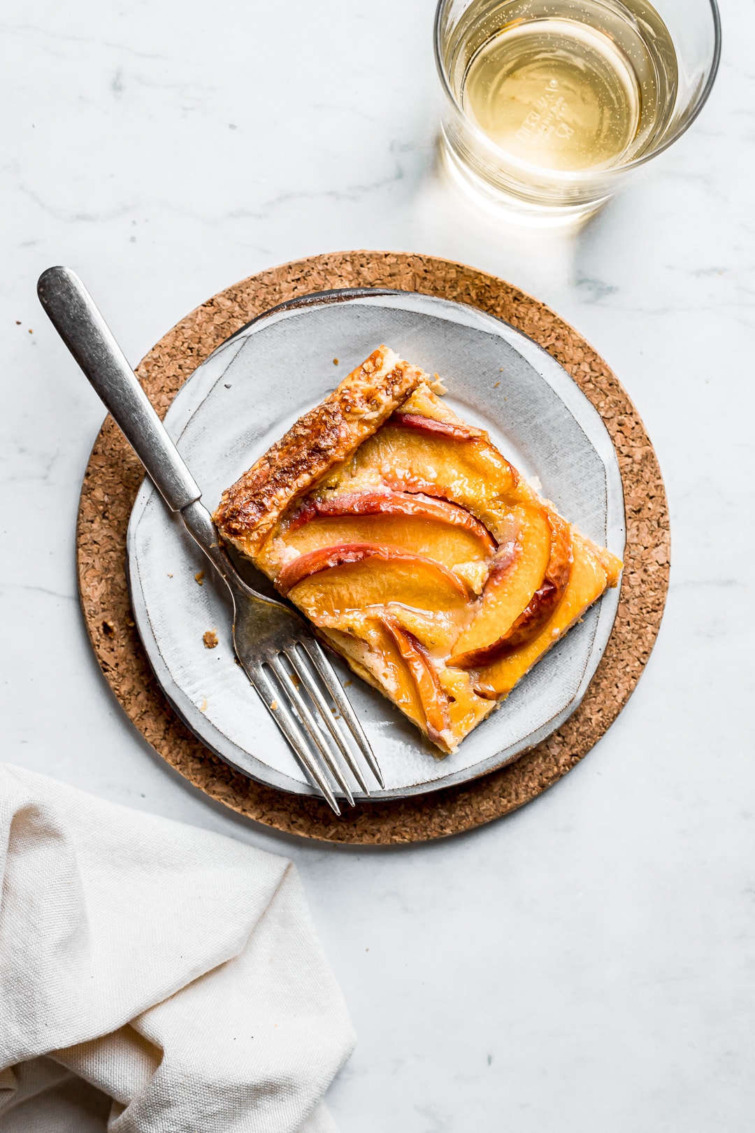 Slice of peach galette on plate with marble background