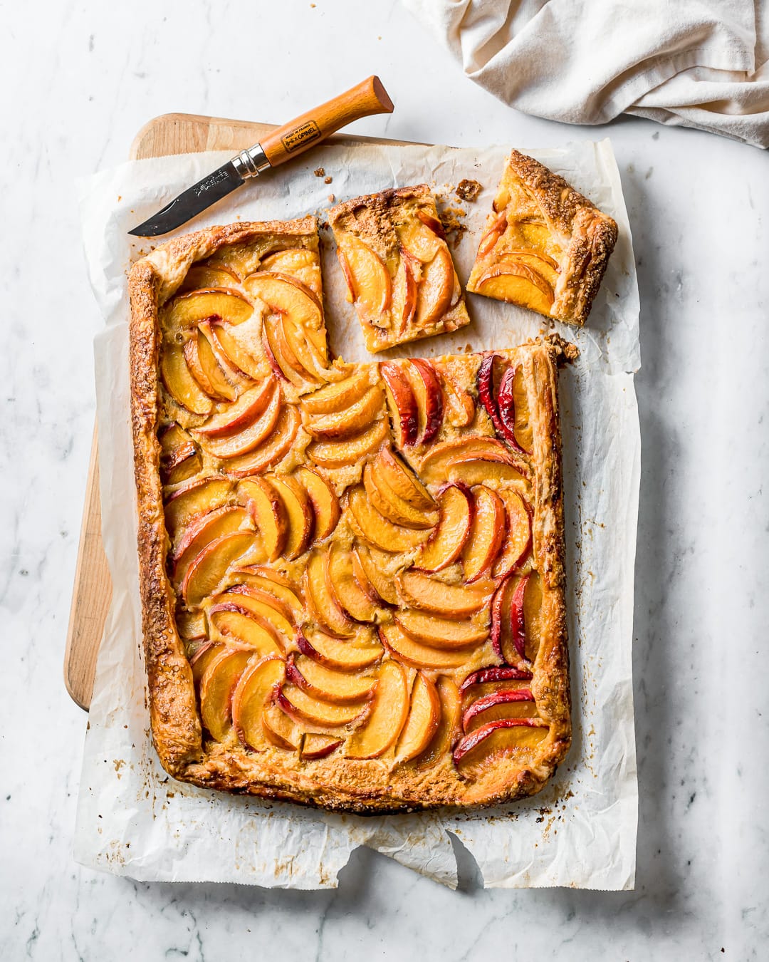 Top view of baked galette with slices cut out on a white marble background