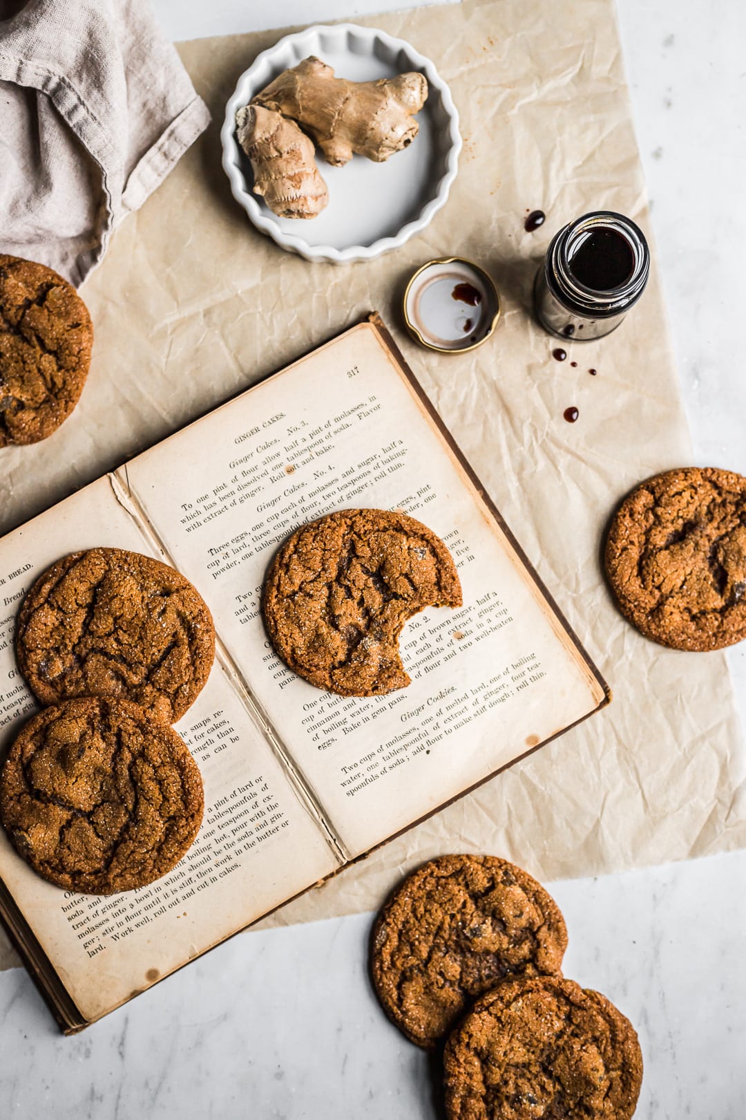 Ginger molasses cookies strewn on a book with natural parchment underneath