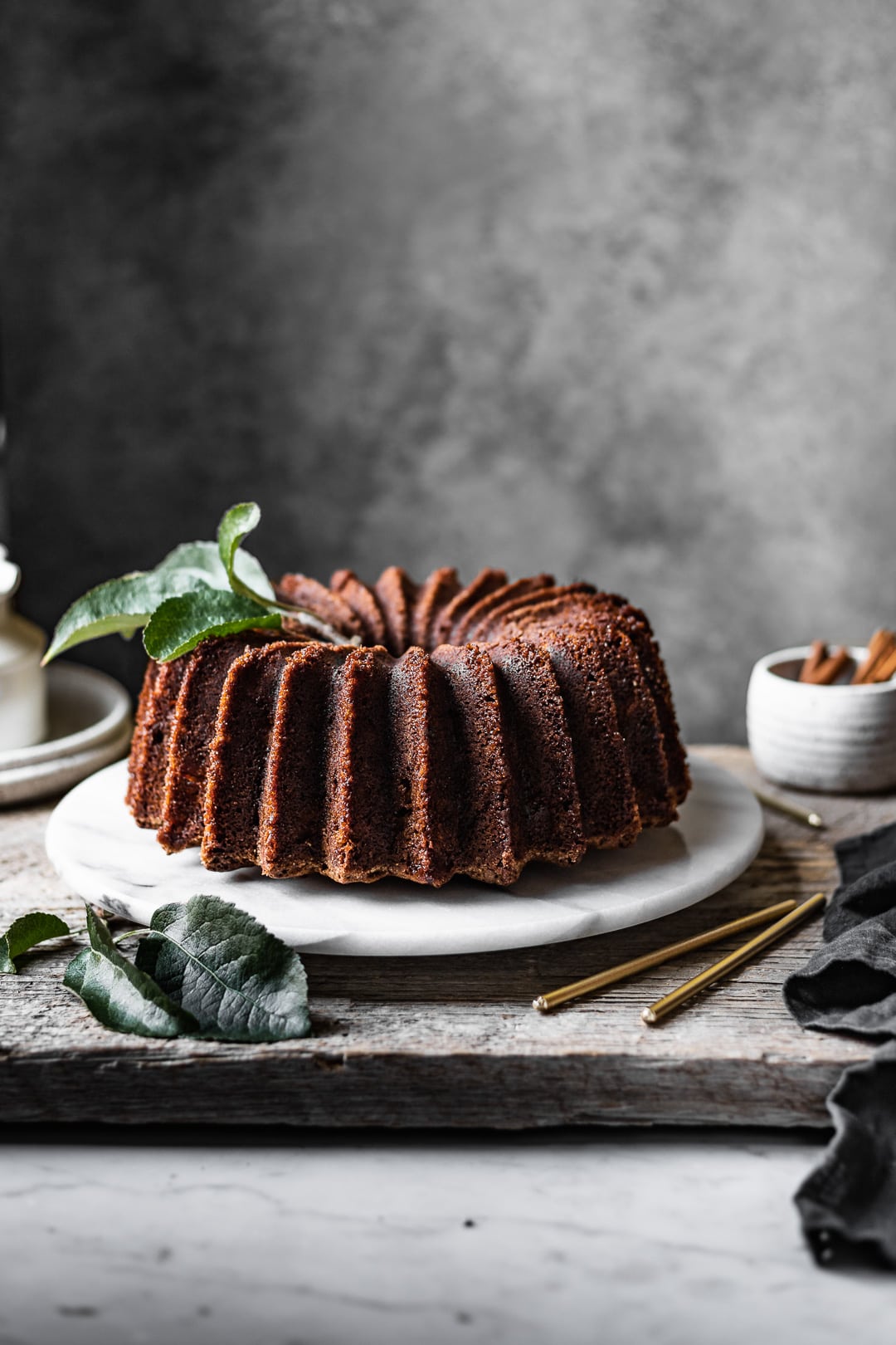 front view of bundt cake on white marble platter with grey background