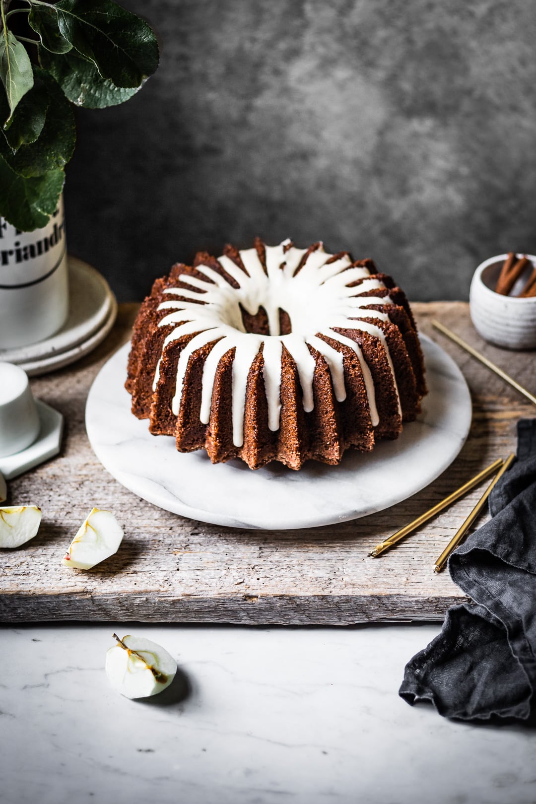 Apple bundt cake with white glaze on a marble platter