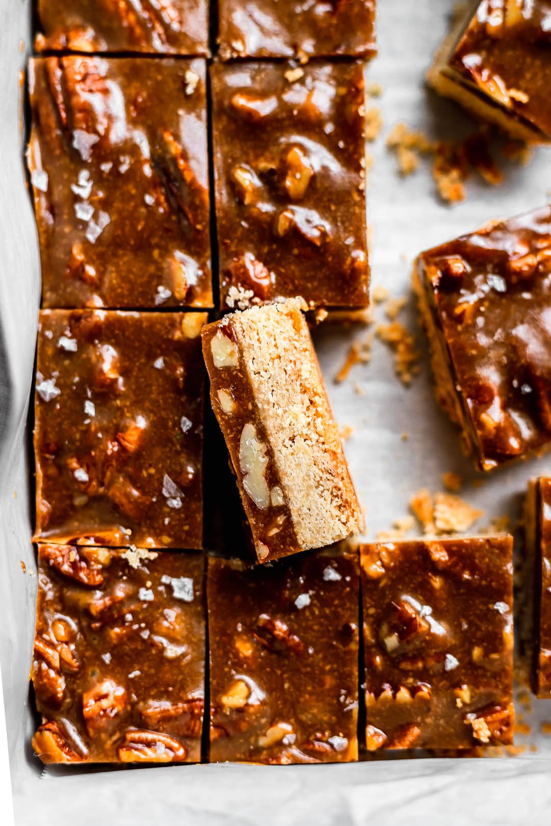 Close up of sliced caramel pecan bars in a pan with one slice turned on its side