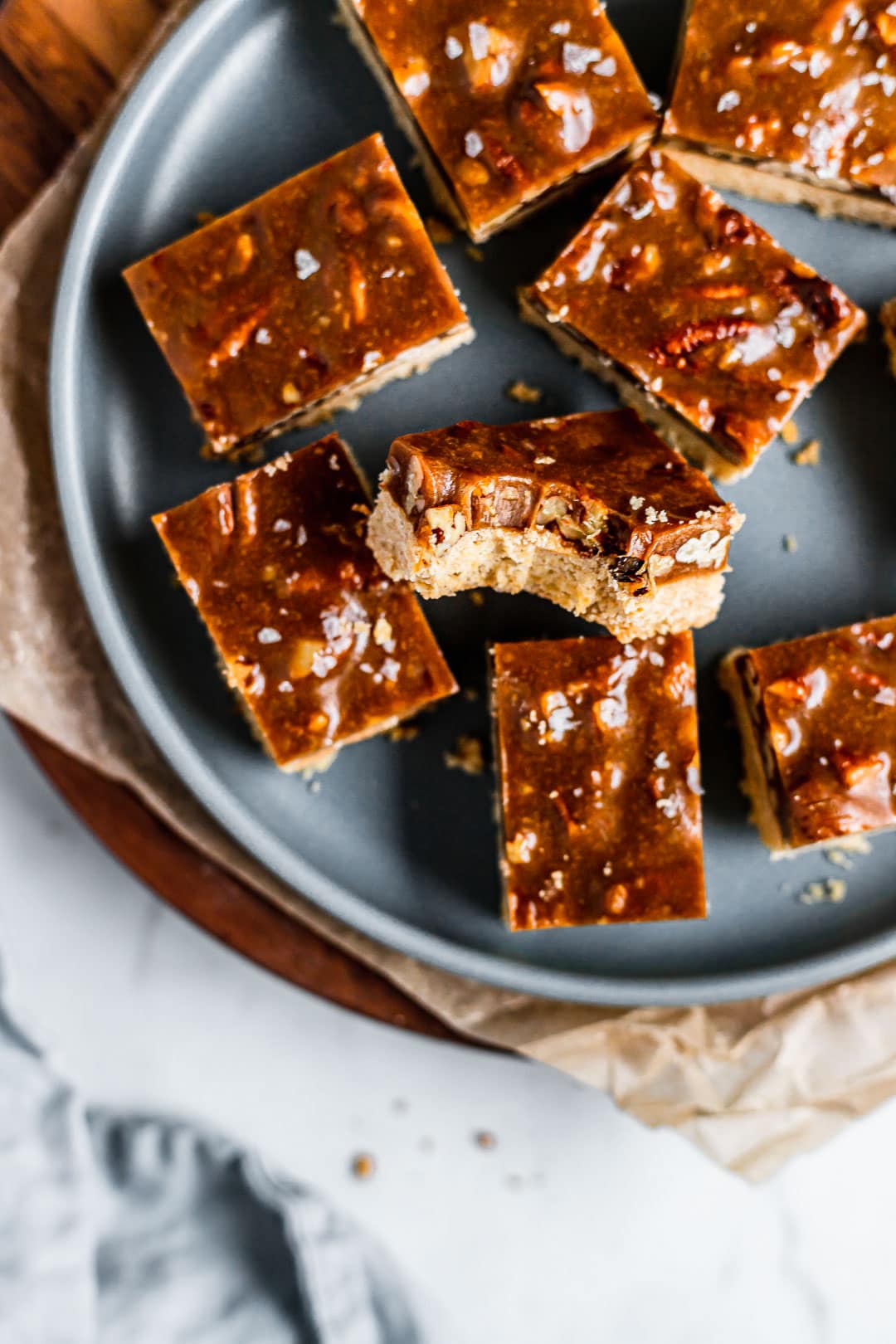 Caramel pecan shortbread bars on a blue plate with a bite taken out of one