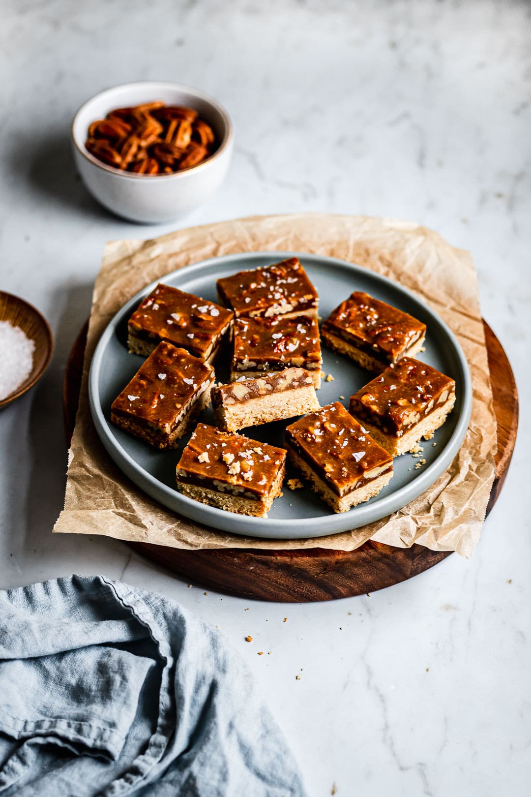 Caramel pecan bars sliced on a plate on a marble surface