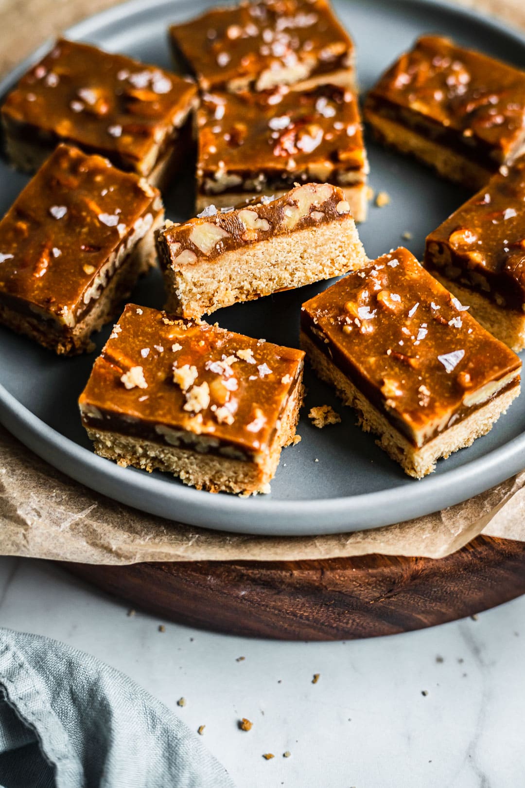 Sliced caramel pecan shortbread bars on a blue plate and marble background