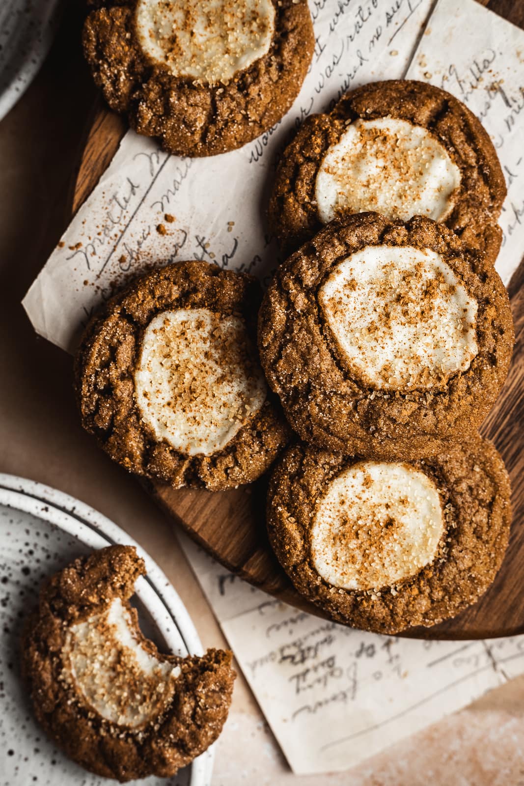 Pumpkin cookies on a wooden board with recipe and partially eaten cookie nearby