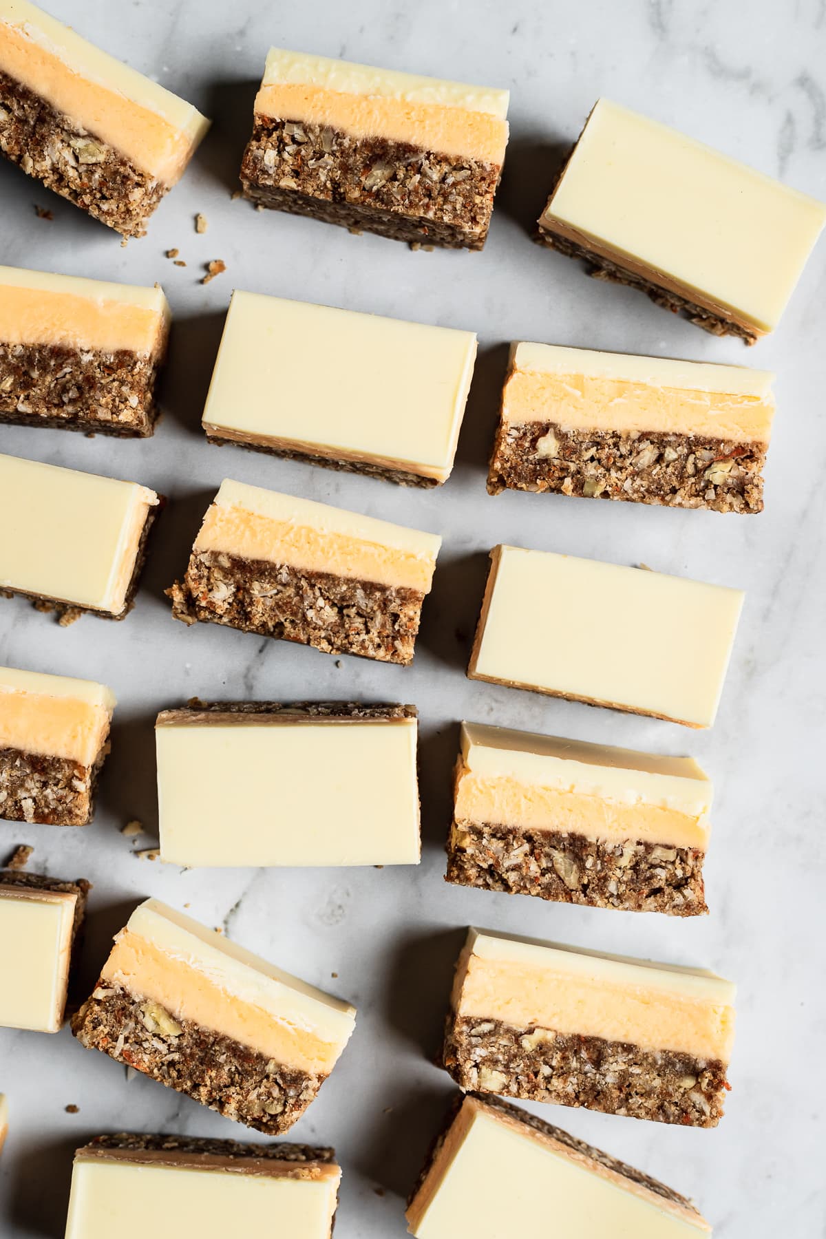 Sliced bar cookies on a white marble background cut into slices with half turned on their side to show the layers