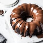 Close up of sliced bundt cake on a white marble background