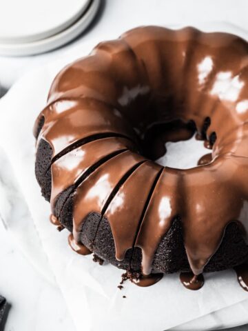 Close up of sliced bundt cake on a white marble background