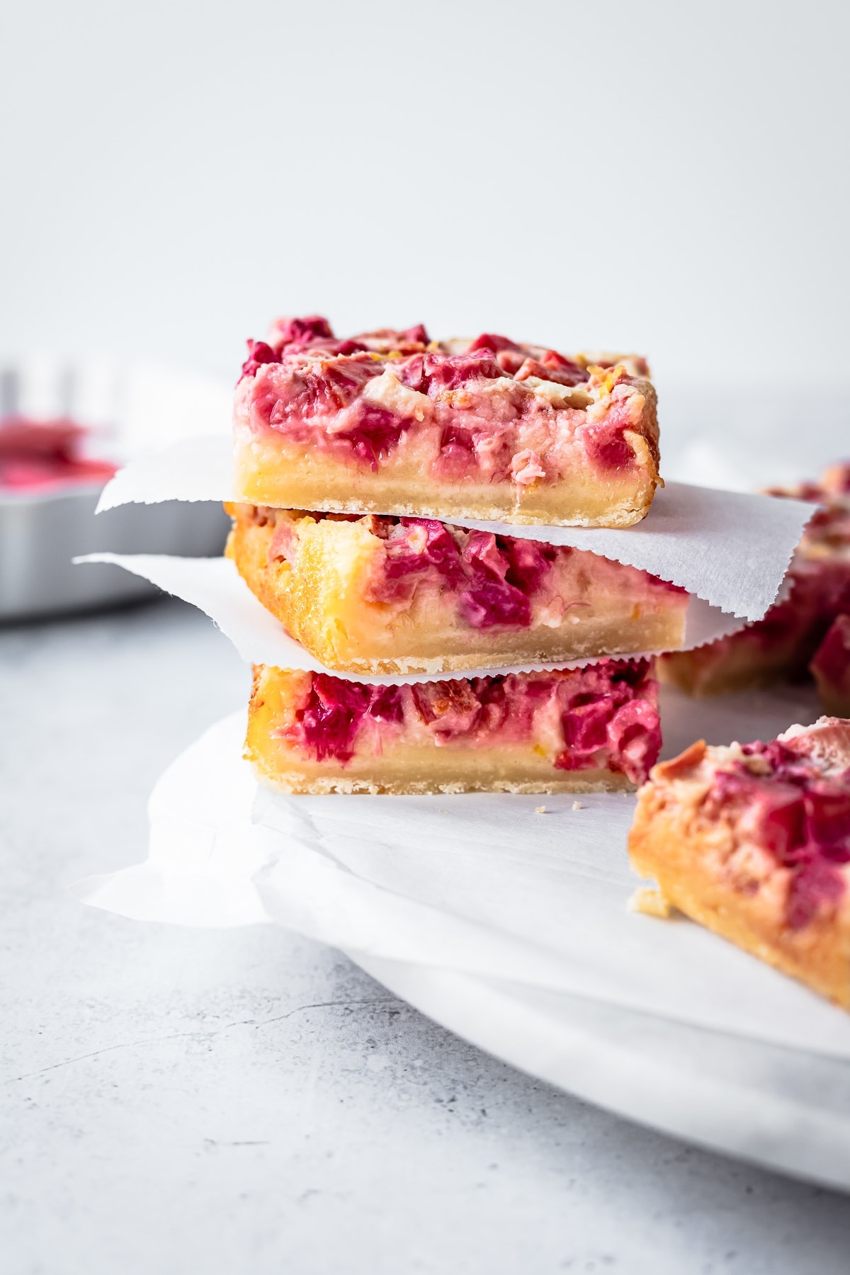 Side view of three stacked lemon rhubarb bars on a white marble platter