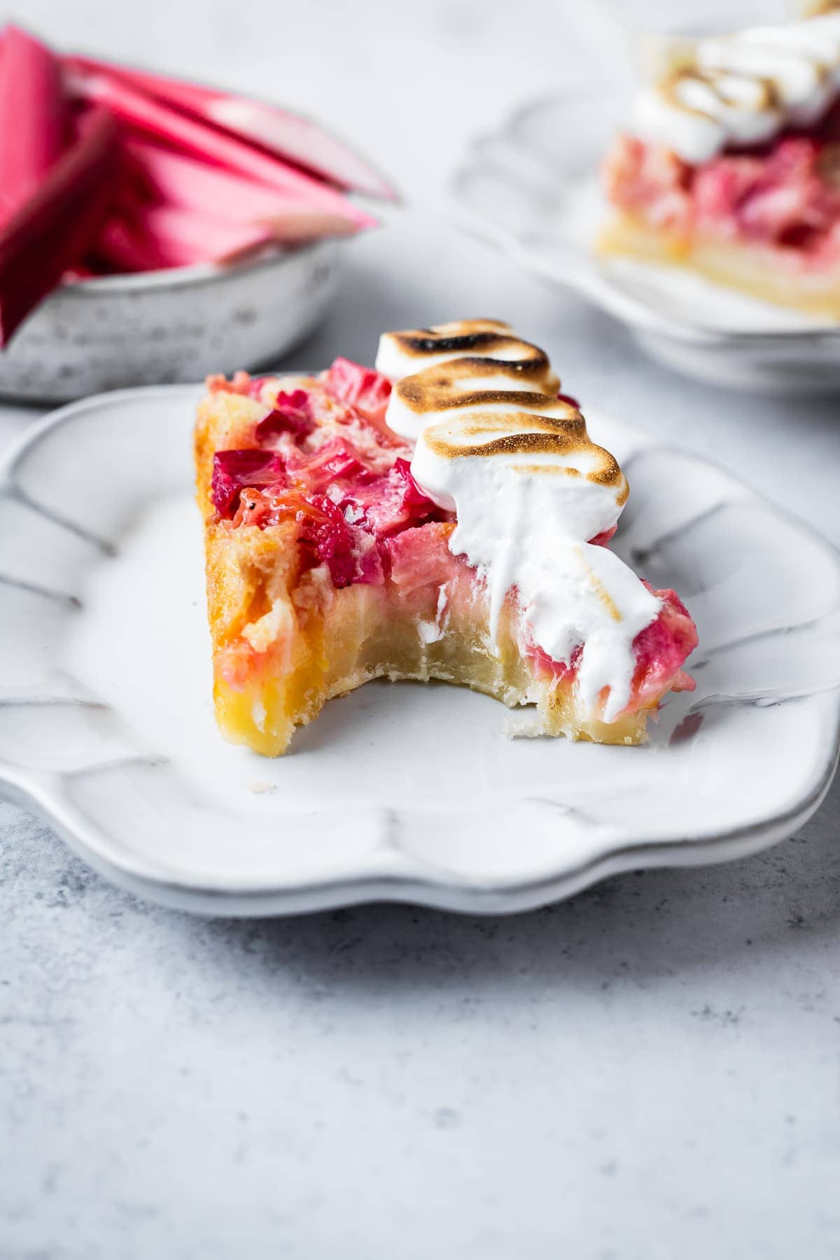 Side view of a lemon rhubarb bar on a plate with a bite taken out of it.