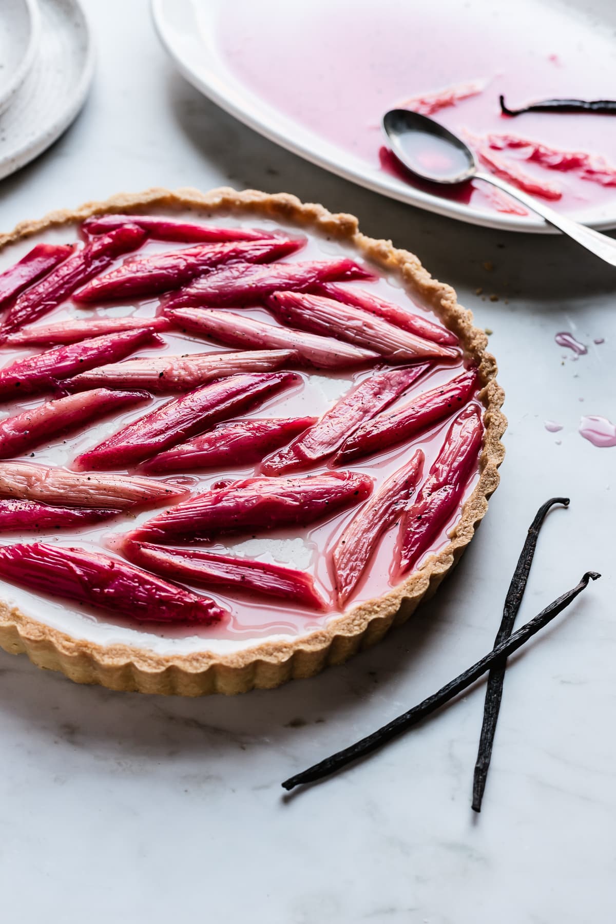 Angled view of panna cotta tart showing the light reflecting off of the poached rhubarb on top