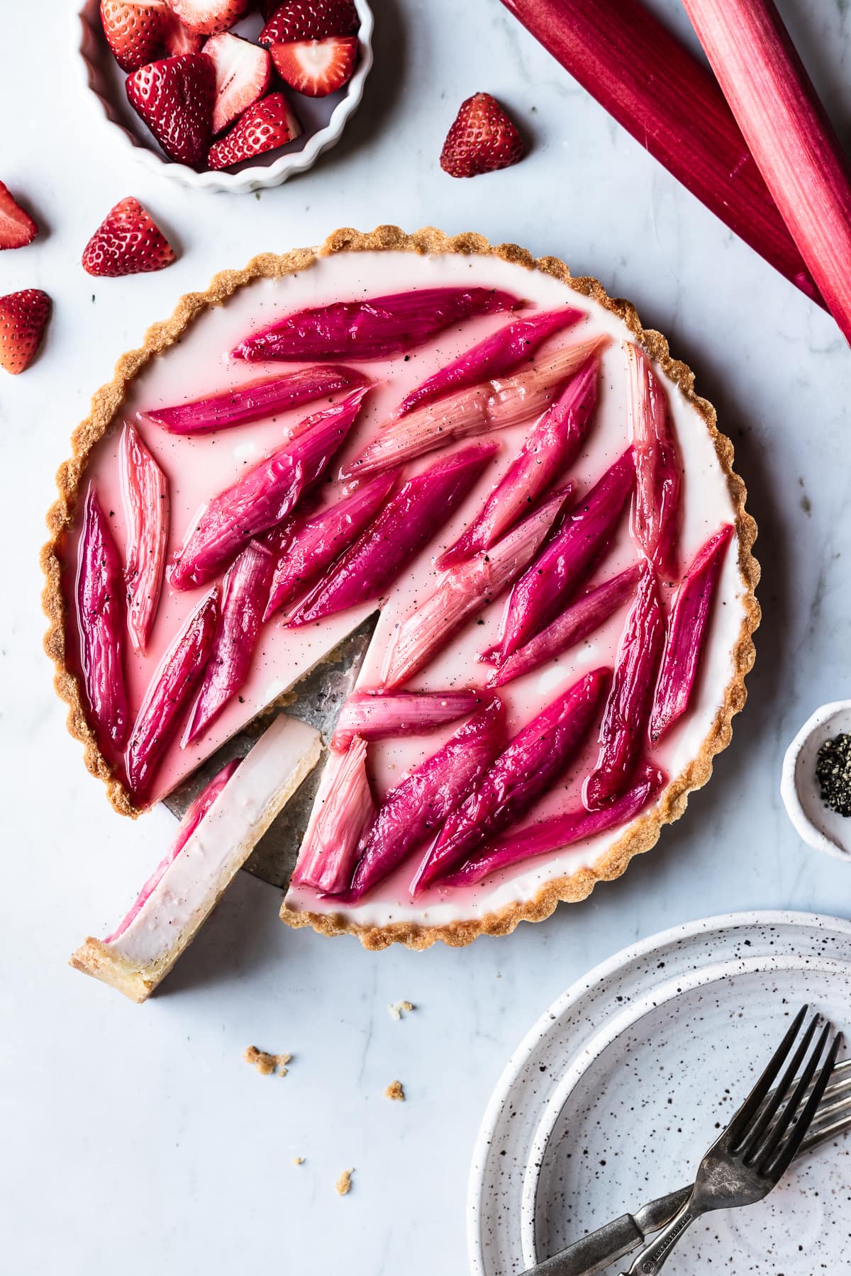 Strawberry rhubarb panna cotta tart with a slice cut out and turned sideways to see the filling