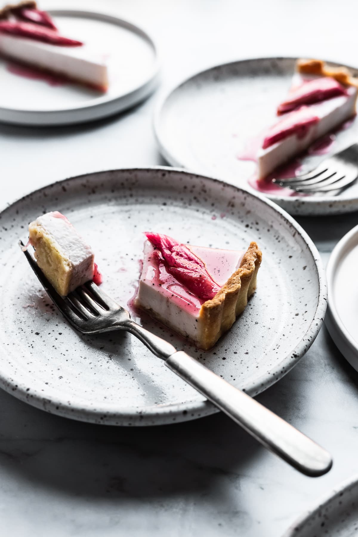 Slices of panna cotta tart on white speckled plates illumnated with backlight