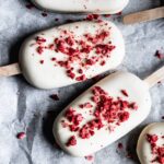 Closeup of strawberry rhubarb ice cream bars covered in white chocolate with freeze dried strawberry bits sprinkled on top