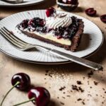 A side view of a slice of chocolate cherry tart on a plate.