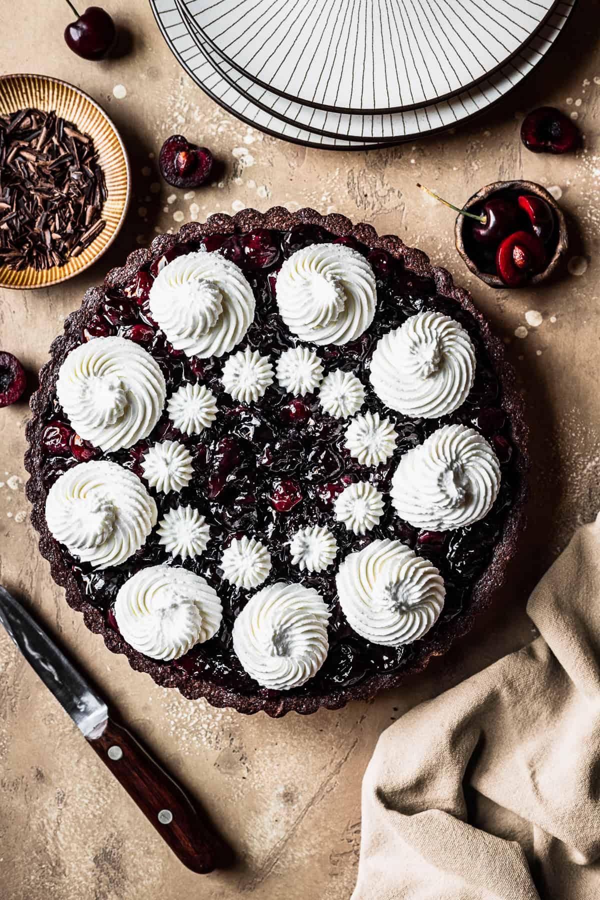 Swirls of whipped cream on top of a cherry chocolate tart.